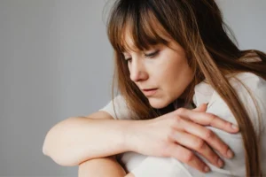 Mujer con expresión pensativa abrazando sus rodillas, reflejando ansiedad sin razón aparente