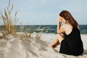 Woman sitting on the beach experiencing anxiety and emotional overthinking