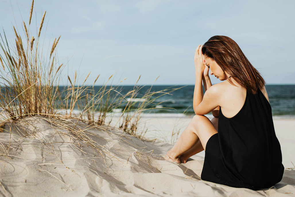 Woman sitting on the beach experiencing anxiety and emotional overthinking